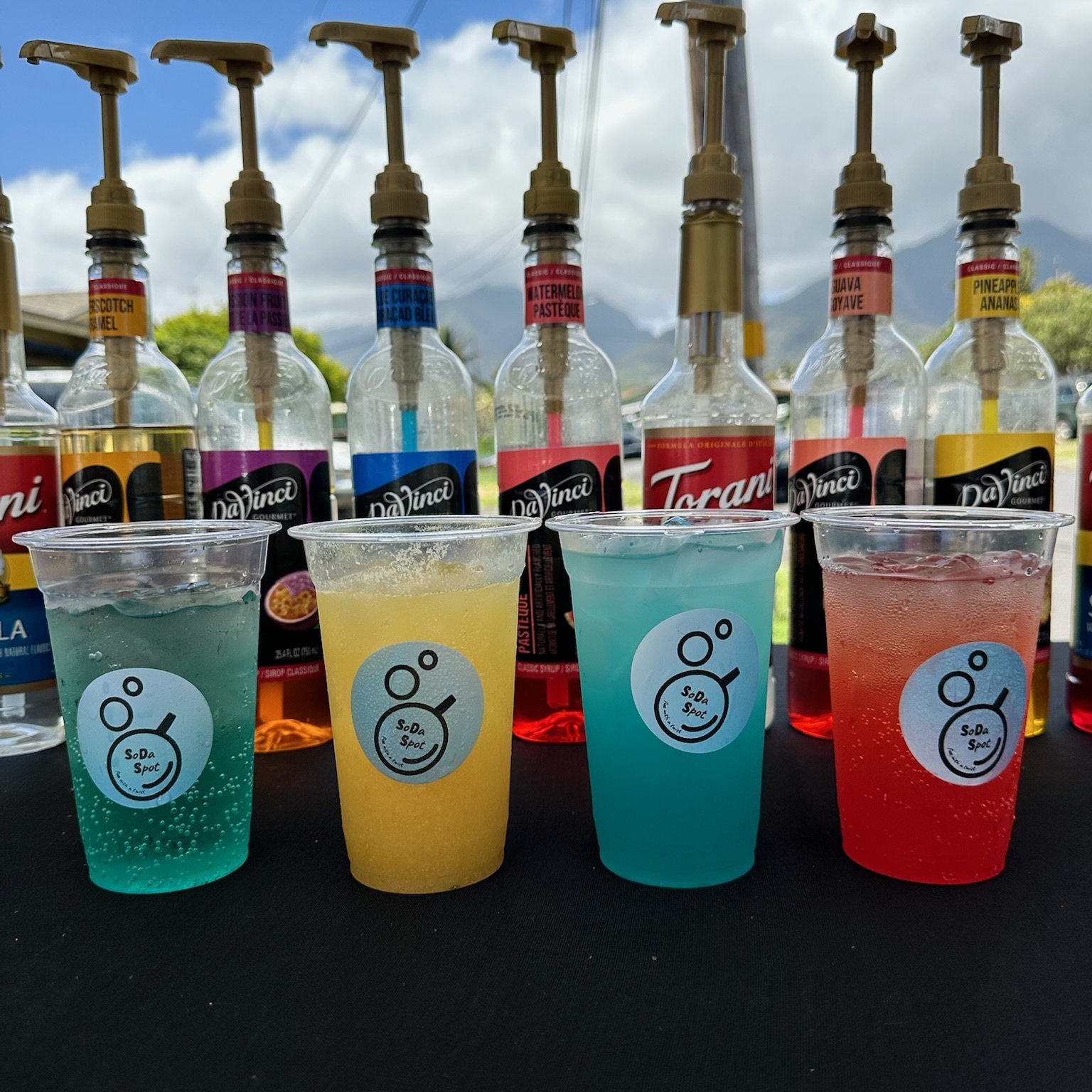 A colorful lineup of SoDaSpot drinks at an event